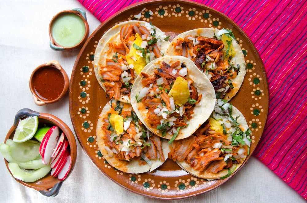 El origen de los tacos al pastor es una historia de migración, fusión cultural y creatividad mexicana. Este platillo se convirtió en uno de los grandes símbolos de la gastronomía mexicana. Descubre cómo nació, por qué se sirve en trompo y cómo conquistó al mundo.