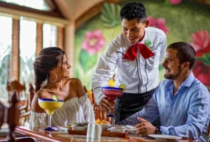 Meseros atienden a turistas en restaurante.