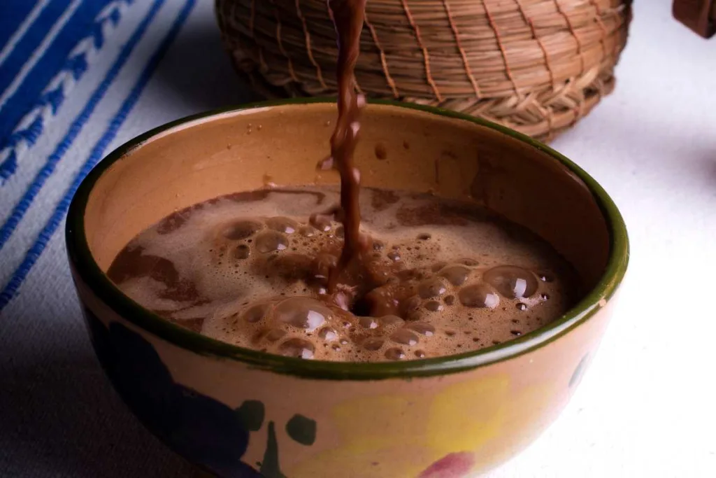 Mucho antes de las tazas cremosas que conocemos actualmente, el cacao ya se bebía en Mesoamérica. En Oaxaca, preparar chocolate con agua mantiene viva una tradición que atraviesa siglos de historia y continúa presente en hogares, mercados y celebraciones. ¿Te gusta este chocolate o prefieres el de leche?